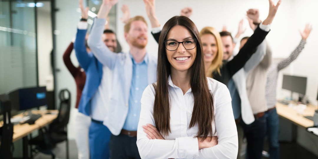 Der Schritt vom Teamvertreter zum Teamleader bedeutet, Verantwortung zu übernehmen, Entscheidungen zu treffen und das Team erfolgreich zu motivieren. Mit klarer Vision, Empathie und Führungsstärke wächst aus einem Mitarbeiter eine inspirierende Führungskraft, die Ergebnisse sichtbar macht.</p>
<p>Bildbeschreibung: Eine Frau mit langen Haaren und Brille steht lächelnd mit verschränkten Armen im Vordergrund, während mehrere Kolleginnen und Kollegen im Hintergrund jubelnd die Arme hochreißen.